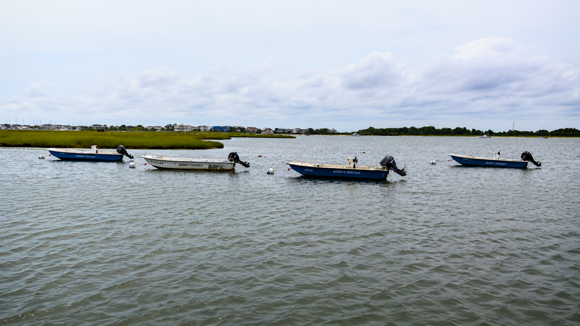 Harbor with small boats moored beside a concrete pier under a cloudy sky