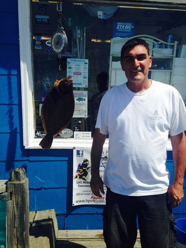 Man standing outside a blue storefront with a bird perched on a sign beside him