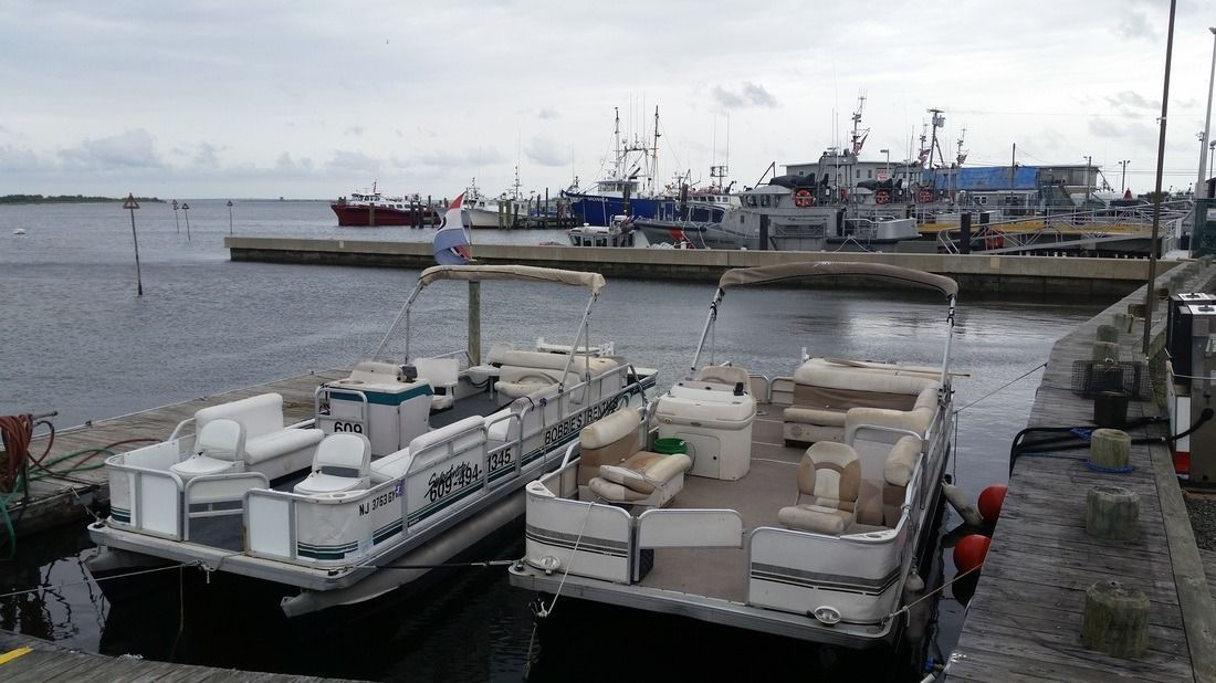 Harbor with small boats moored beside a concrete pier under a cloudy sky