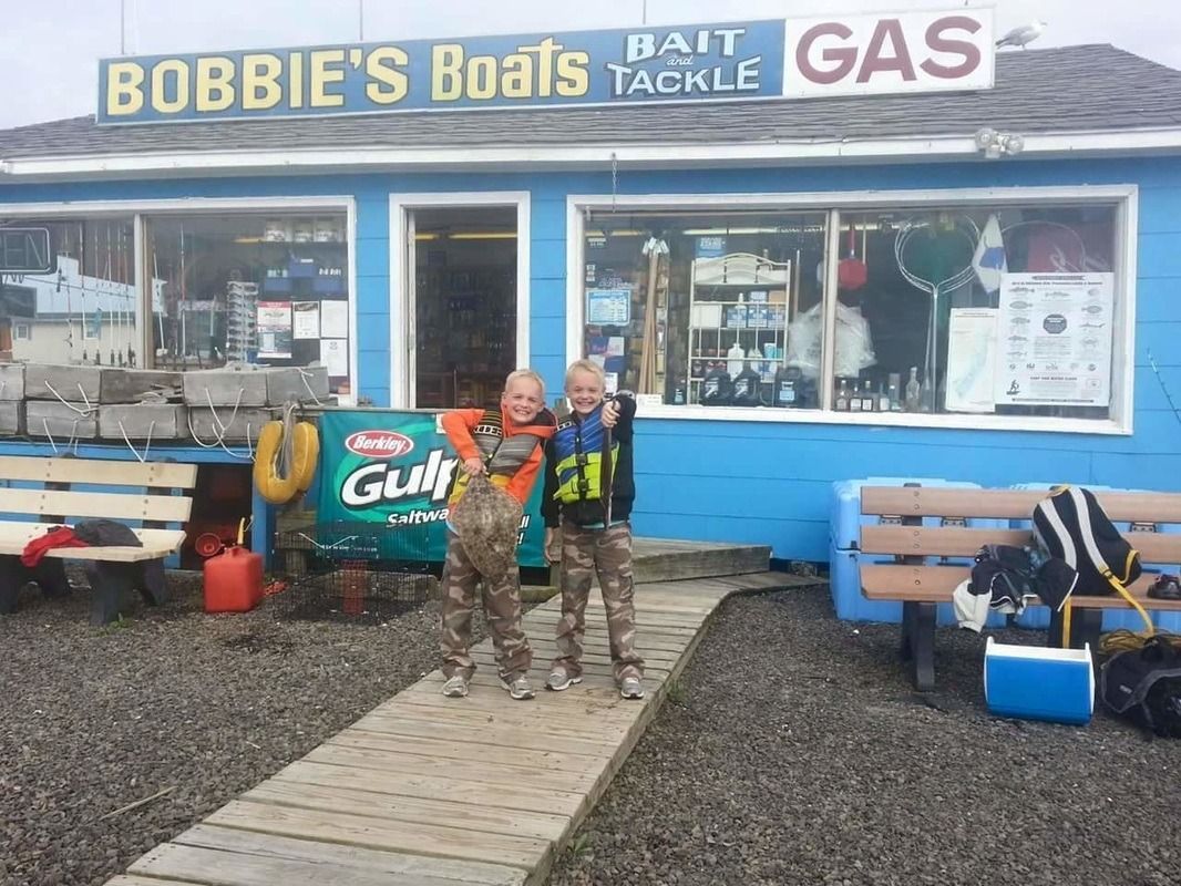 Two people stand outside Bobbie’s Boats bait and tackle shop by the entrance sign.