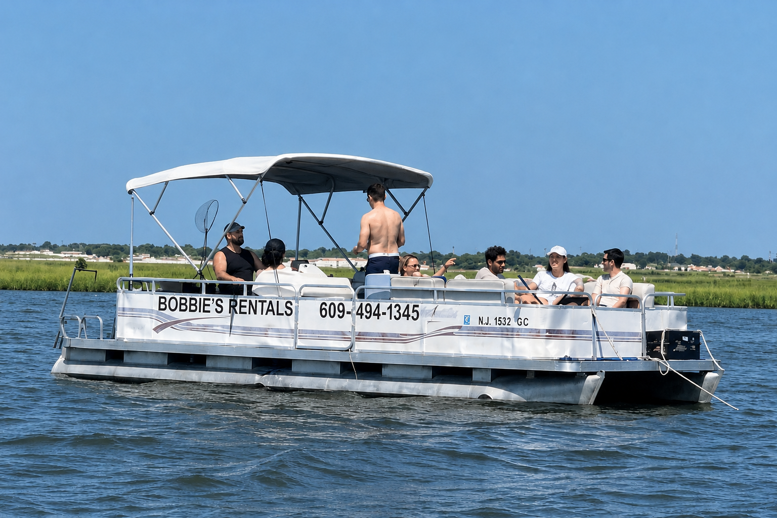 Pontoon boat with several people cruising on a calm lake under a clear blue sky
