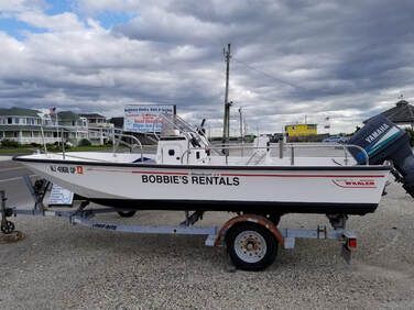 White rental fishing boat on a trailer, with “BOBBIE’S RENTALS” on the hull, under a cloudy sky.