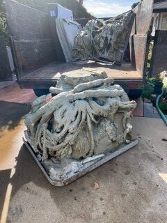Concrete debris, possibly a damaged sculpture, in the bed of a truck. Gray and white colors dominate.