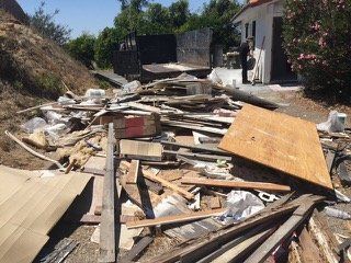 Pile of construction debris in front of a building; a person is standing by a black truck.