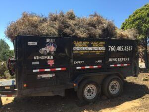 Black trailer filled with brown brush, advertising 