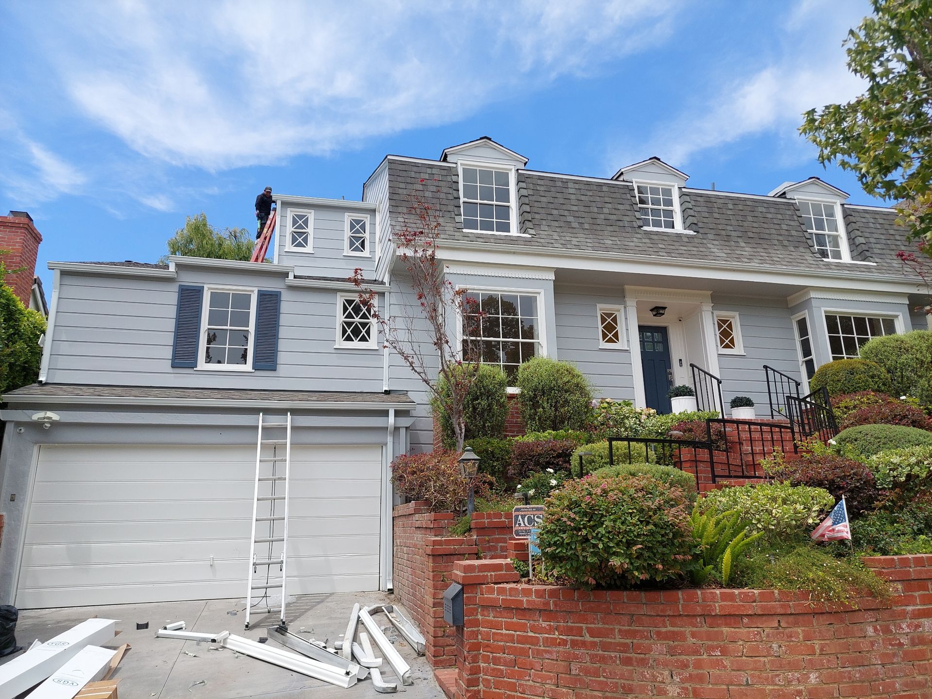 House with white siding and red brick steps, front porch, and garage under a blue sky.