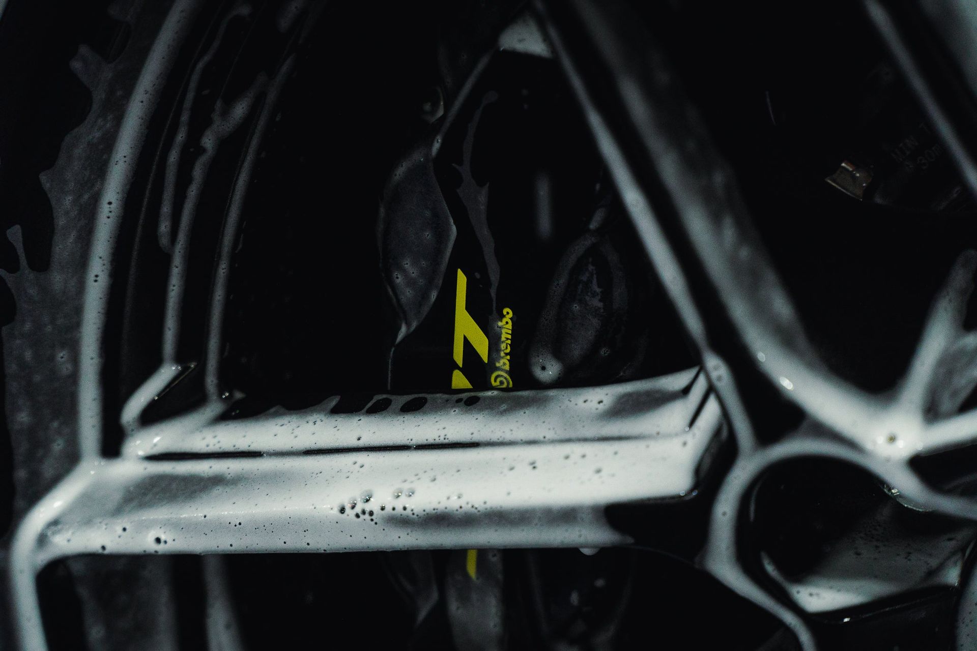 Close-up of a black alloy wheel rim with a yellow brake caliper behind it.