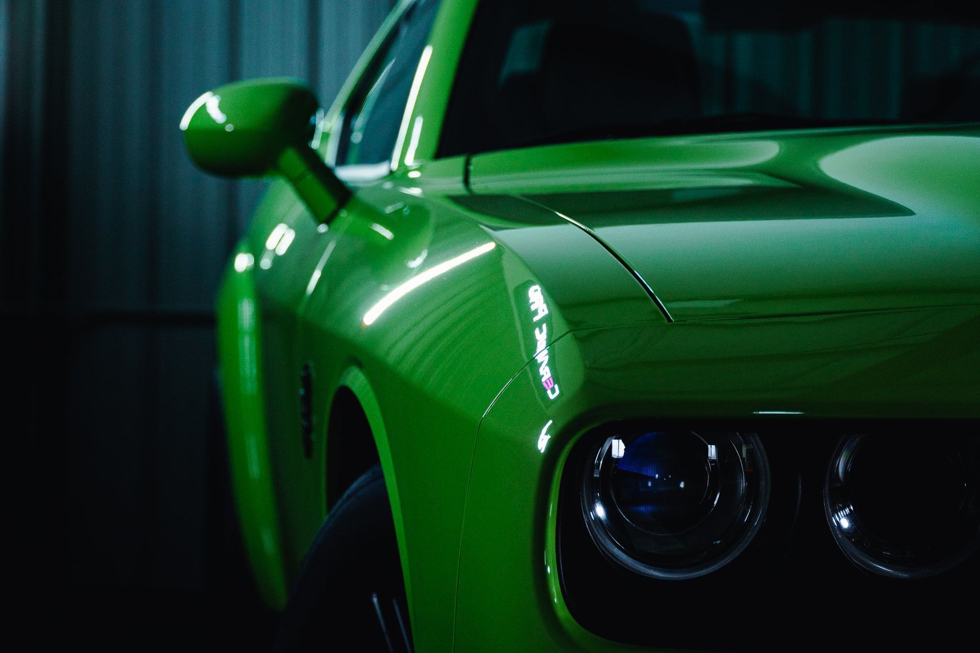 Close-up of a bright green sports car front in low light