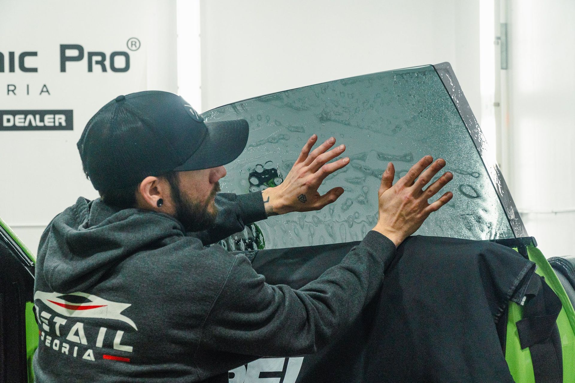 Man in a black cap and jacket handling a large wrapped panel in an indoor workshop