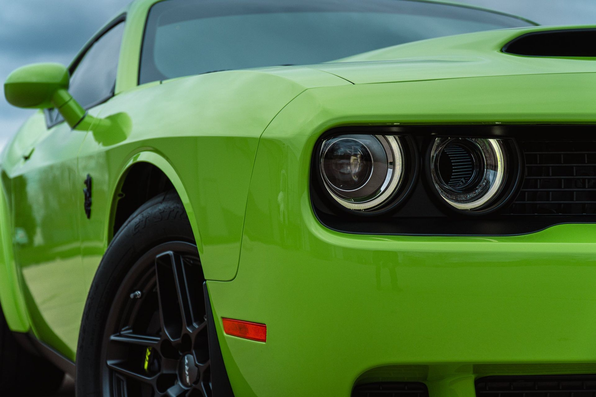 Bright green sports car front view with black wheels and round headlights