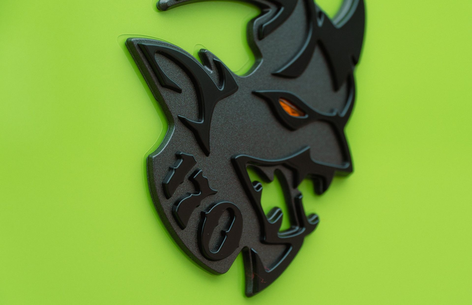 Black wolf logo with orange eye on a bright green background
