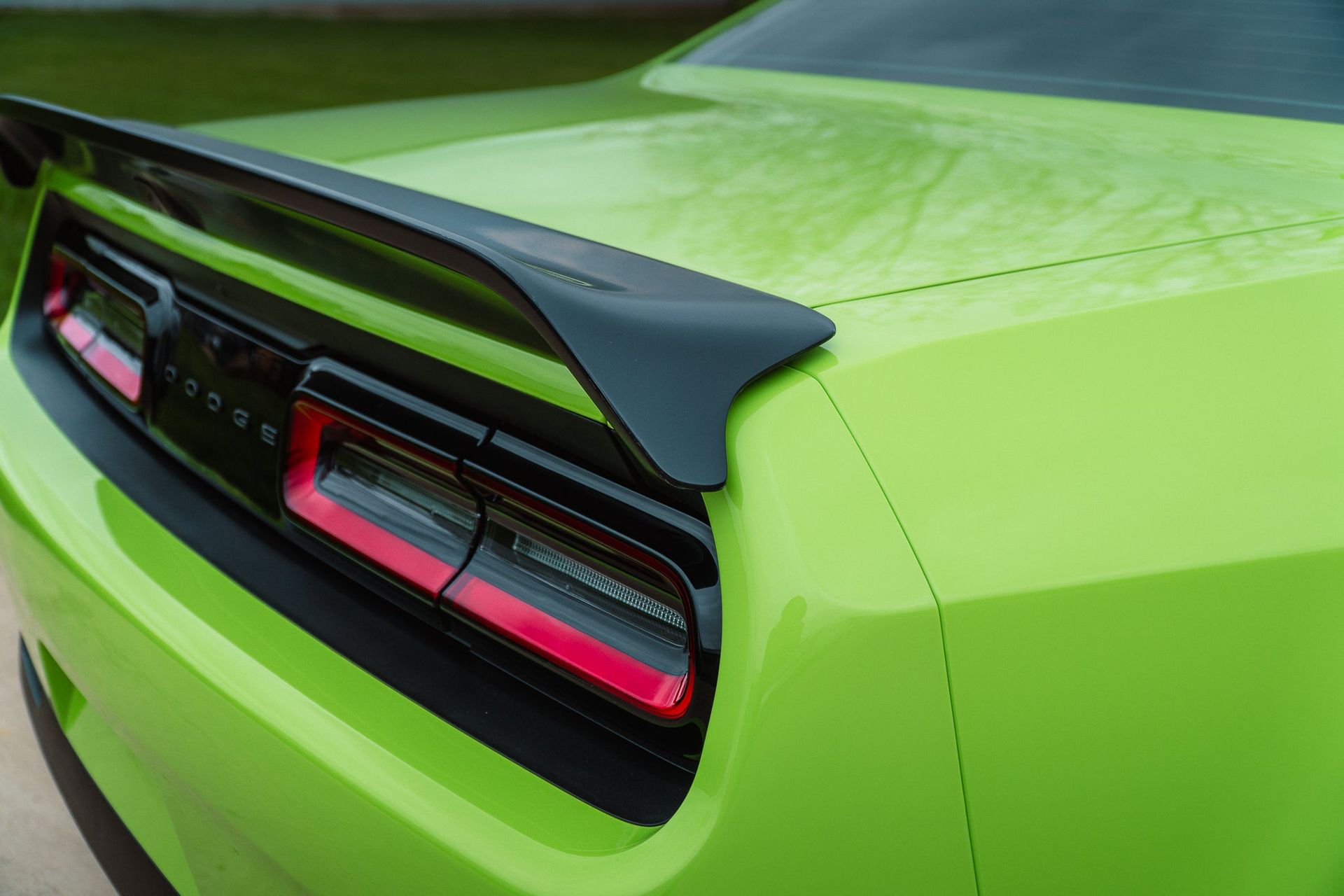 Close-up of a lime green sports car rear with black spoiler and red taillights