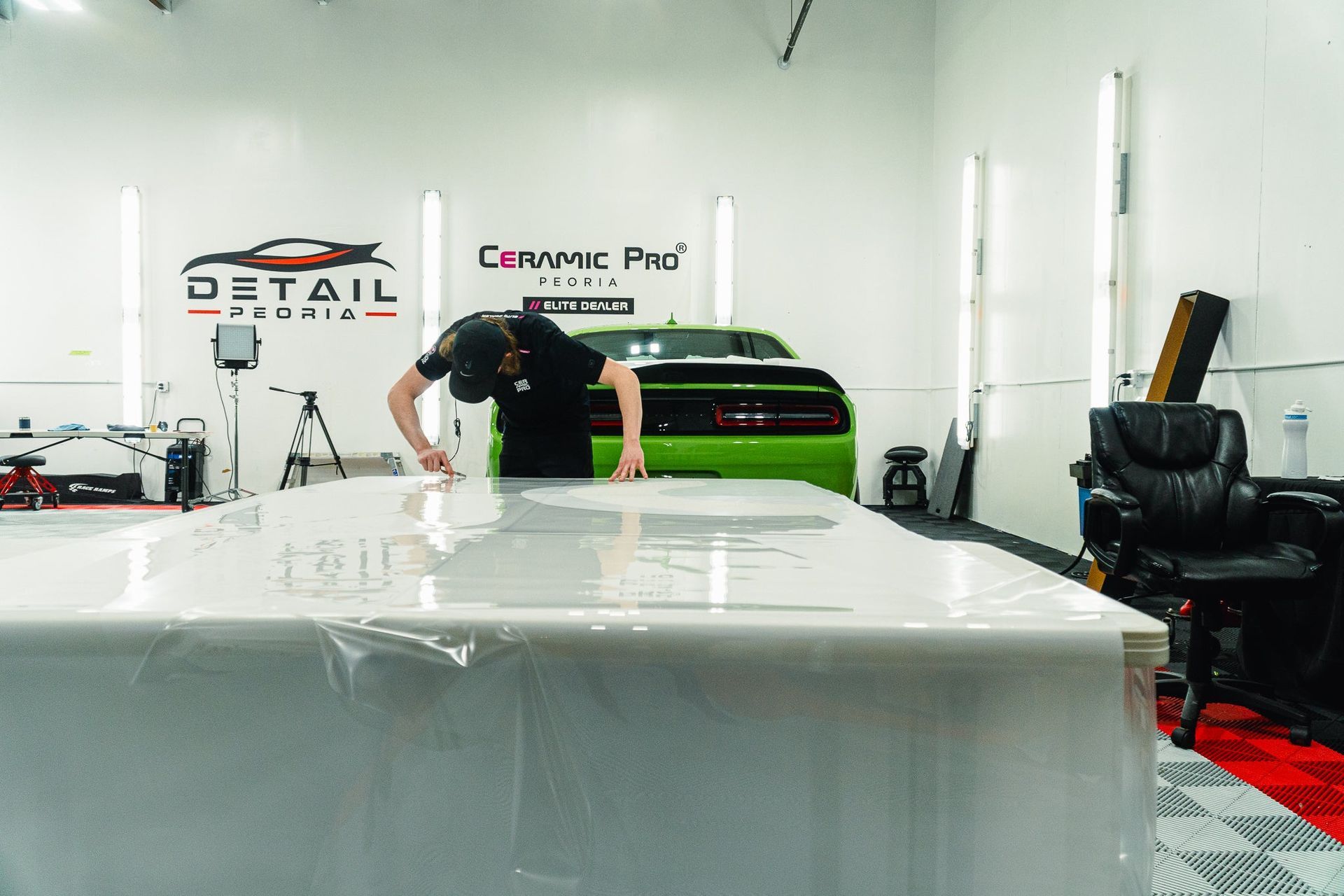 Man polishing a green car in a bright auto detailing shop