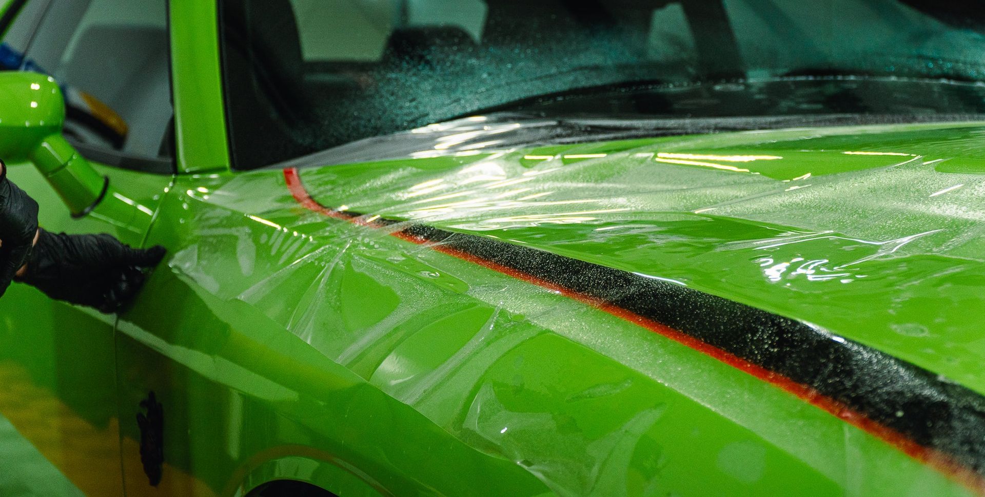 Close-up of a bright green sports car hood with black and red accents