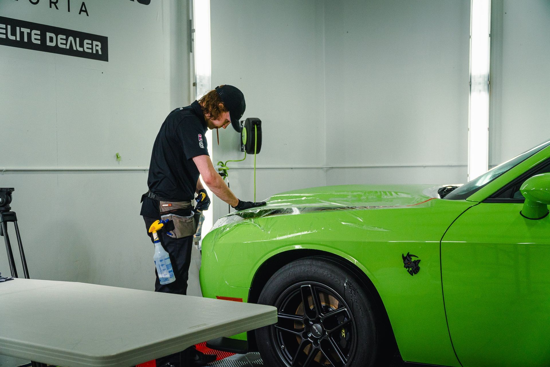 Mechanic detailing a bright green sports car in a workshop