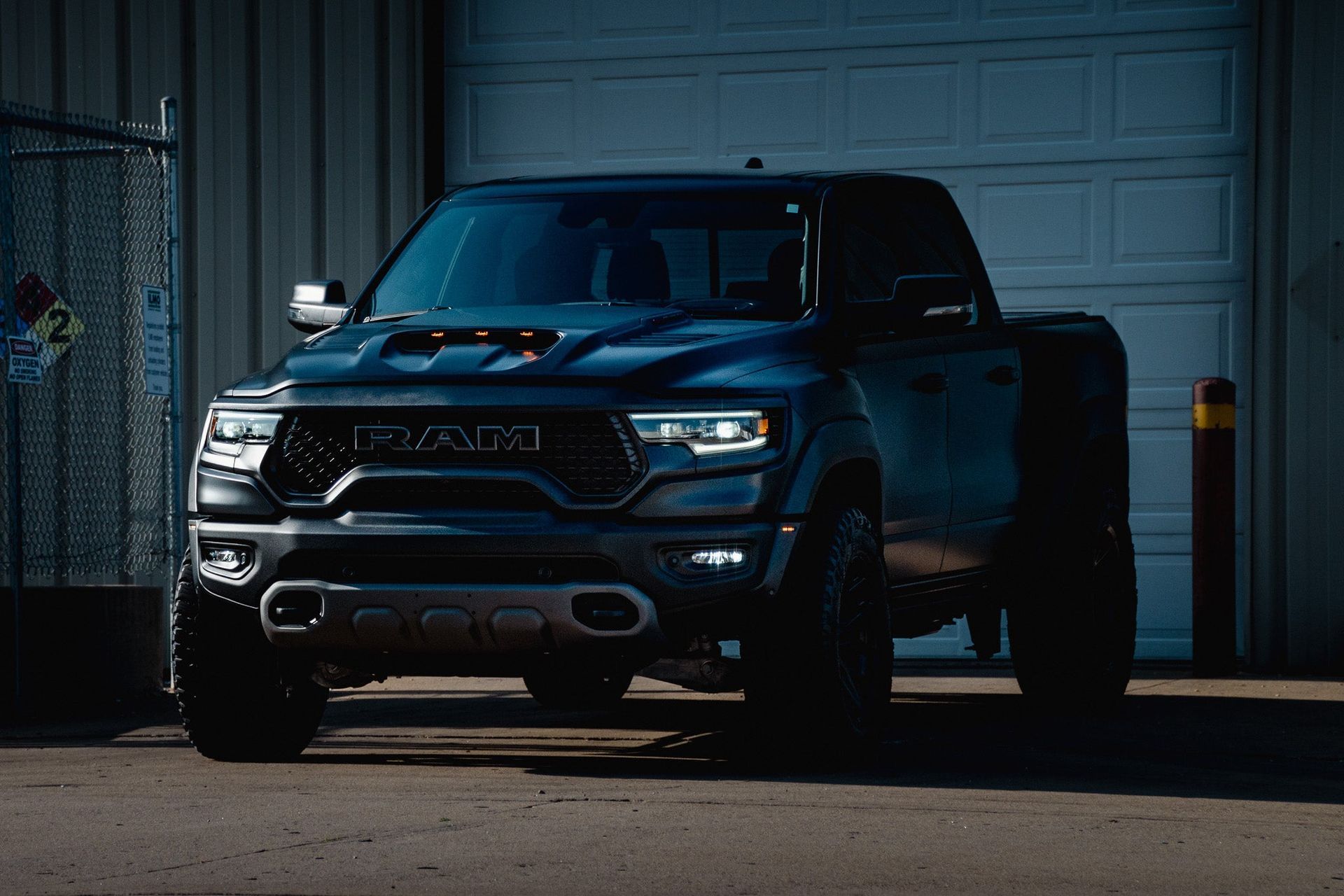 Dark pickup truck parked in front of a garage at dusk