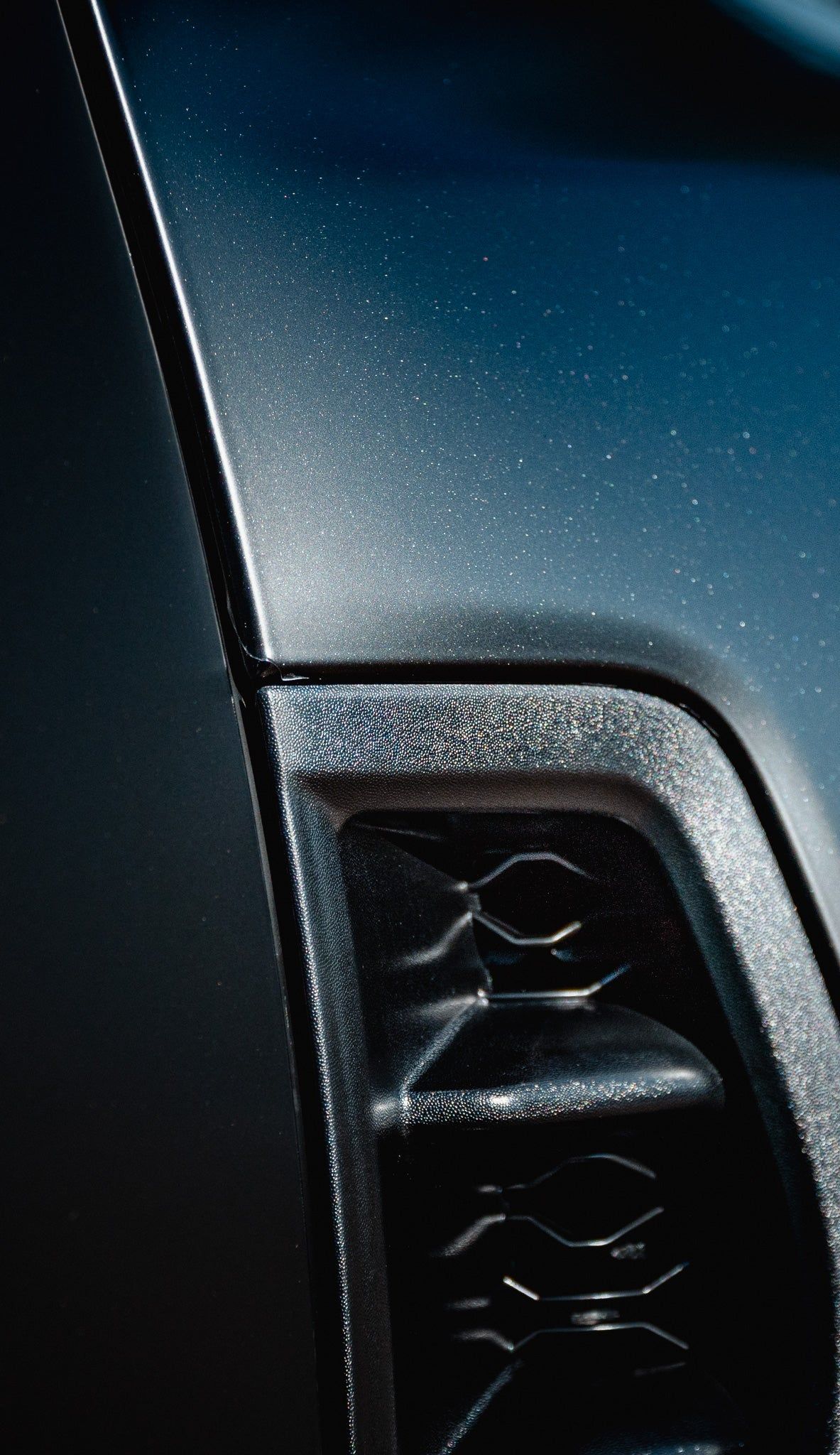 Close-up of a car’s front grille and glossy blue body panel with chrome trim.
