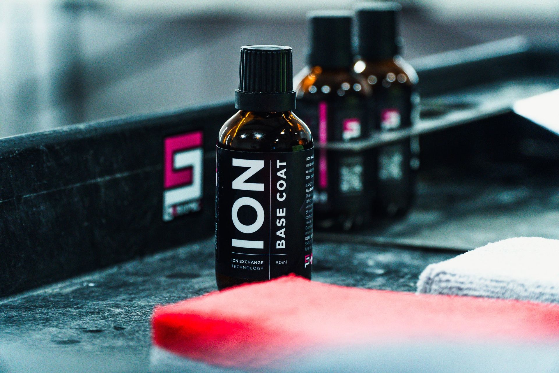 Black bottle labeled “ION” on a gym bench, with two blurred bottles behind it.