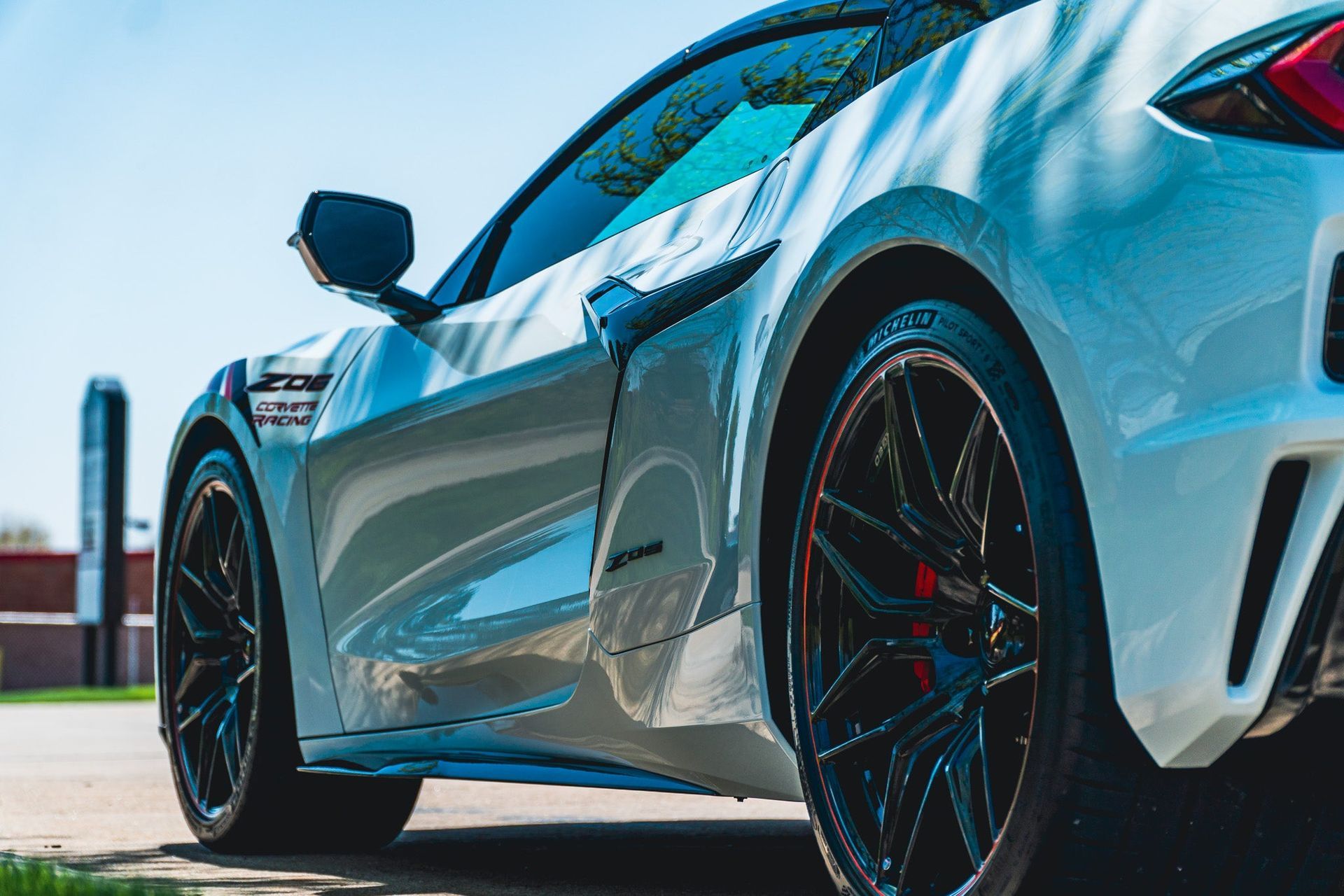 Blue sports car parked outdoors, rear three-quarter view with black rims and red brake calipers