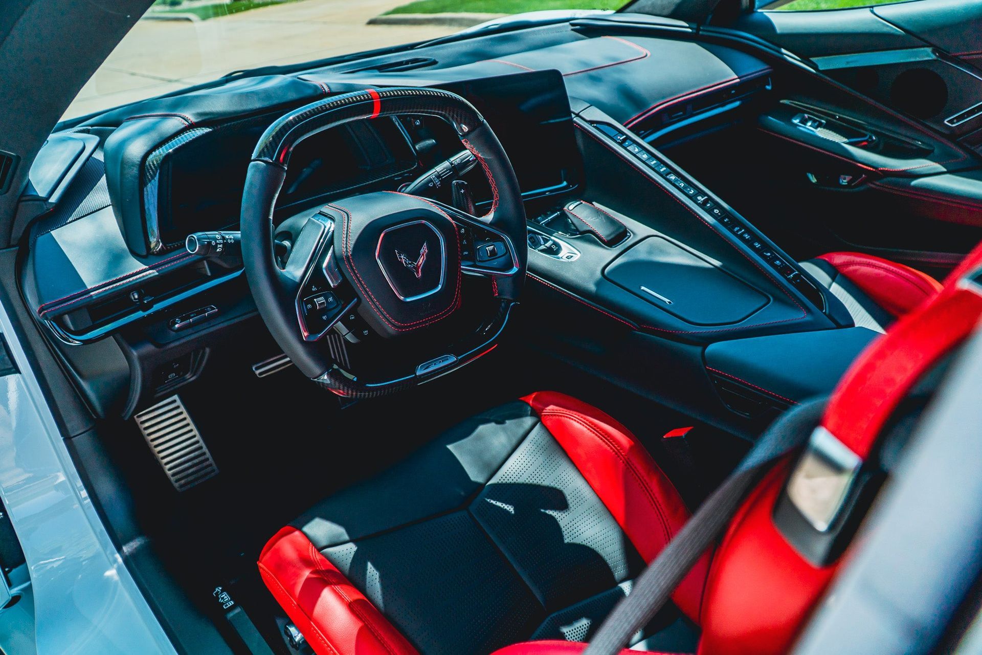 Luxury sports car interior with black and red seats and a steering wheel view of the cockpit
