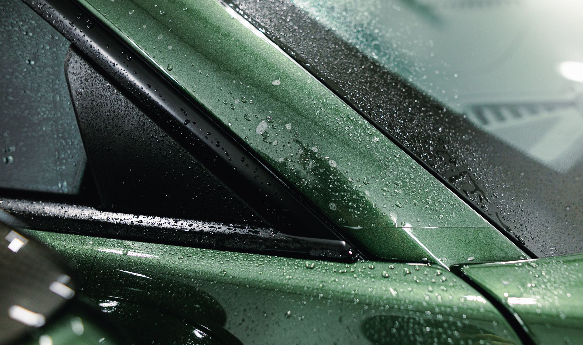 Close-up of a green car door and window covered in raindrops.