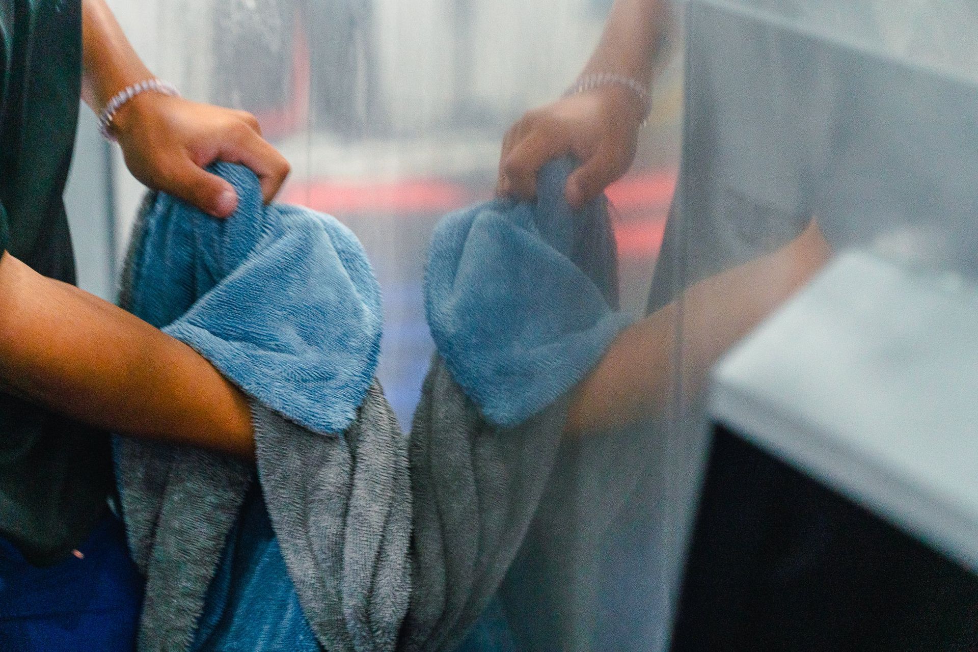 Hands holding blue towels through a shower curtain in a bathroom