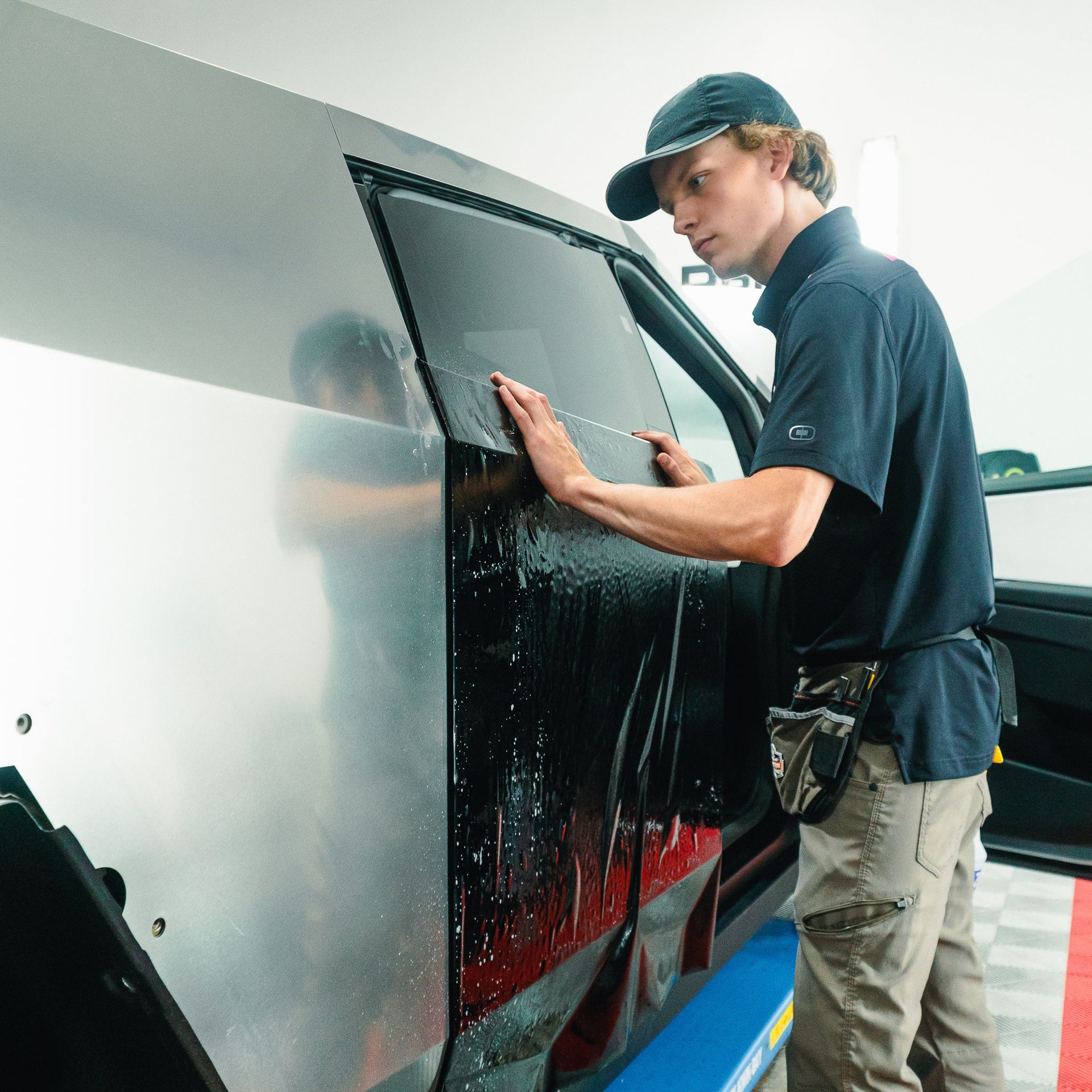 Worker cleaning a large bus window with a cloth in a garage