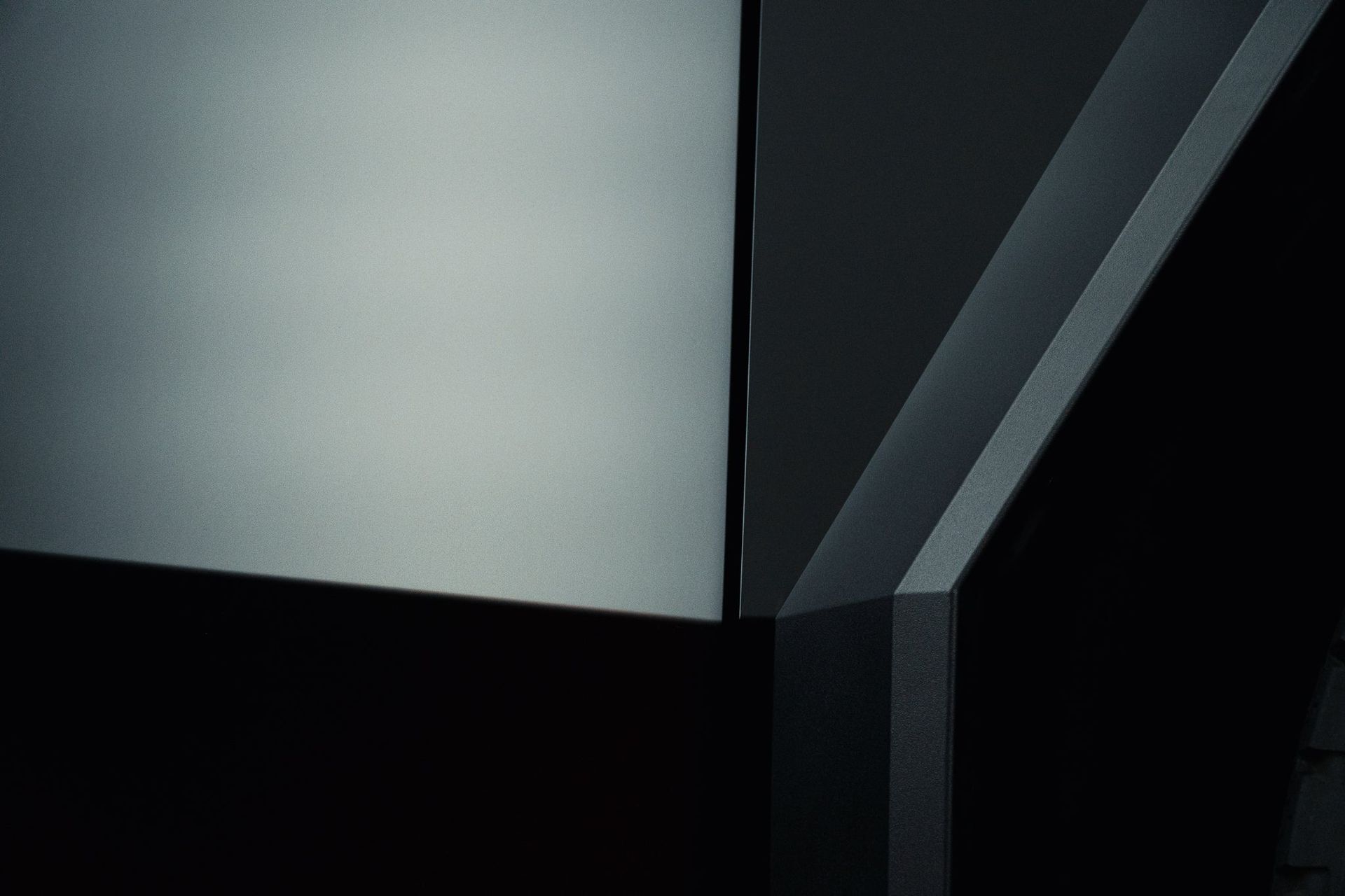 Abstract close-up of a gray and black geometric surface with angled metallic panels