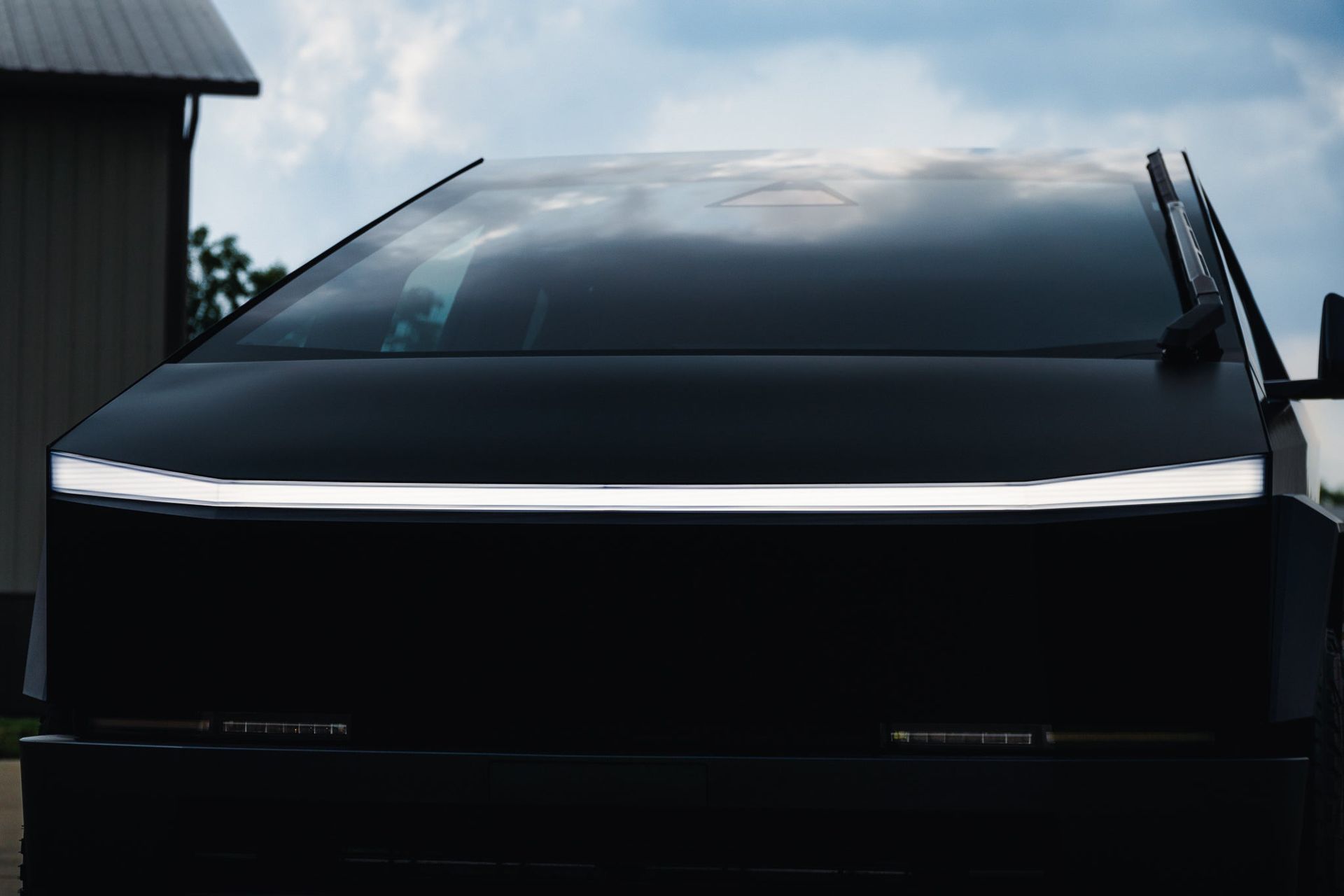 Black SUV with a sleek light strip on the front, parked outdoors beside a building.