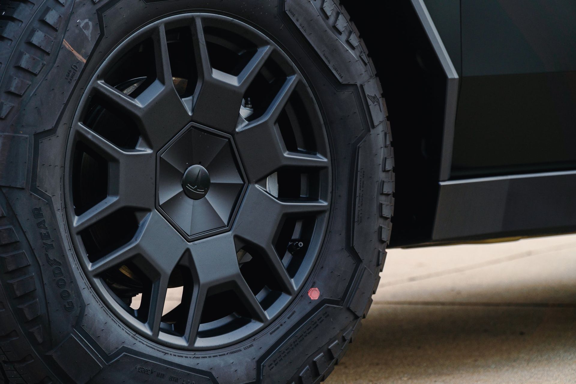 Close-up of a black off-road truck wheel with rugged tire on a paved surface