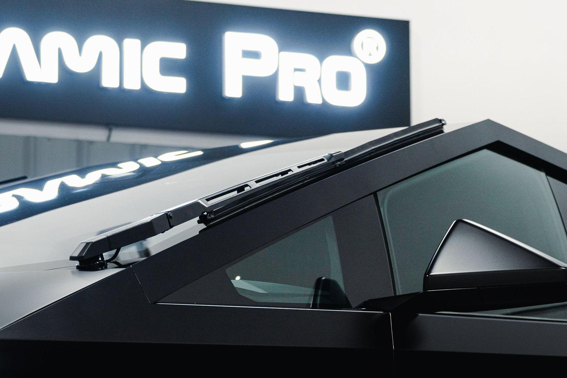 Black angular concept car beside a glowing “AMIC PRO” sign