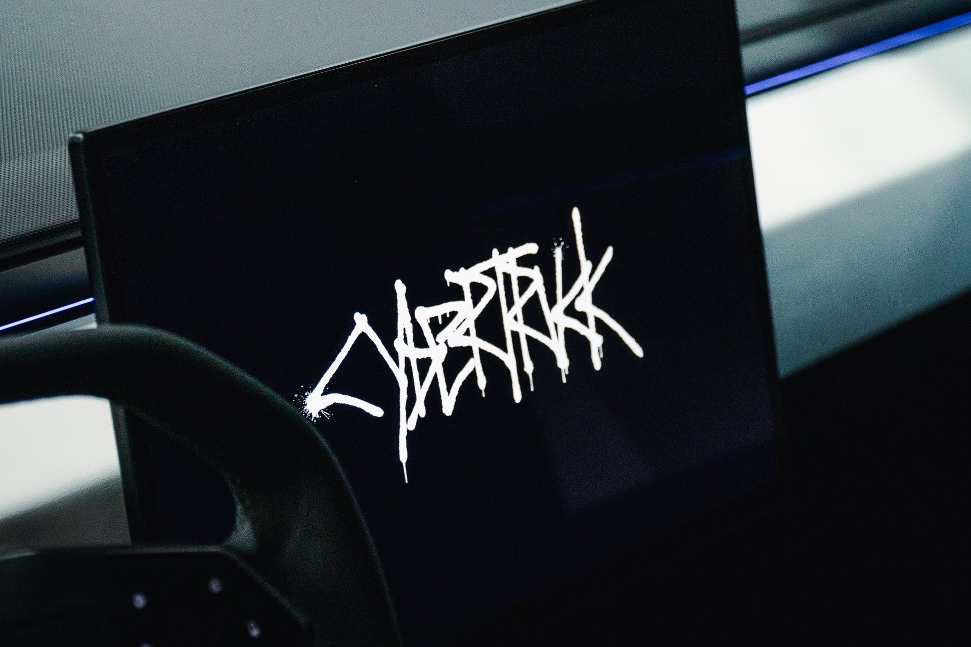Black sticker with white graffiti-style logo on a car dashboard near the windshield