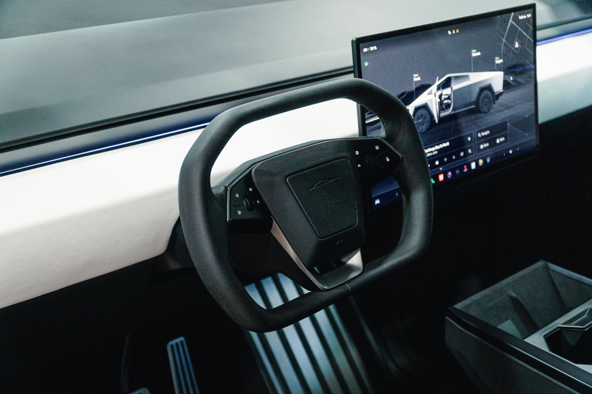 Futuristic car interior with a yoke steering wheel and a large dashboard display showing a vehicle camera view