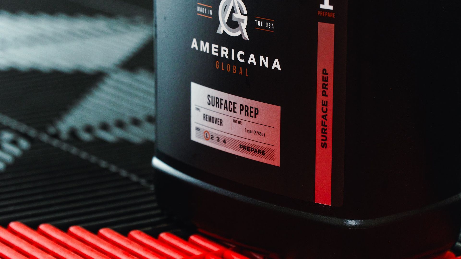 Black supplement tub labeled “Americana” on a red-and-black textured surface.