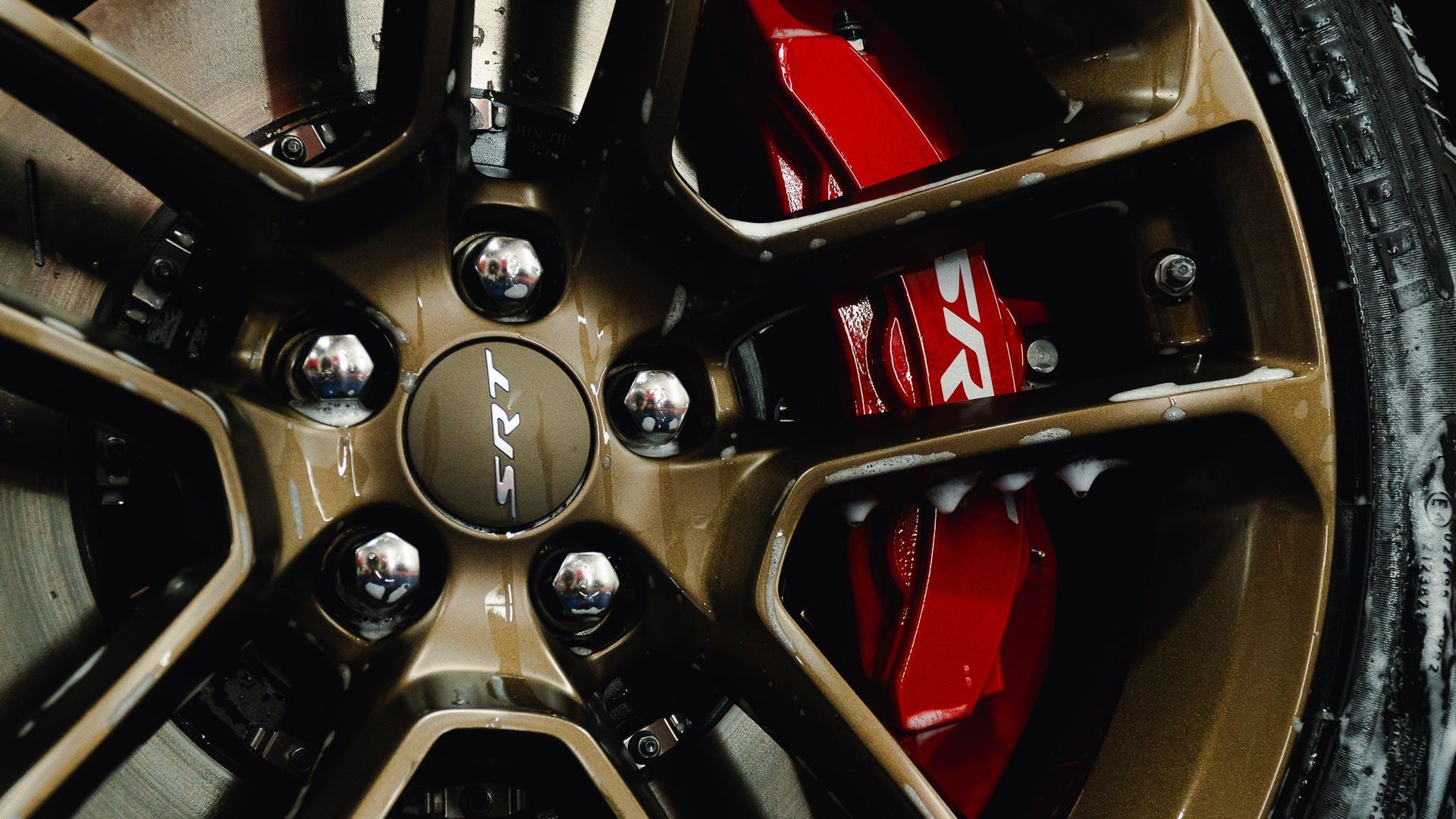 Close-up of a bronze alloy wheel with red brake caliper and black tire spokes