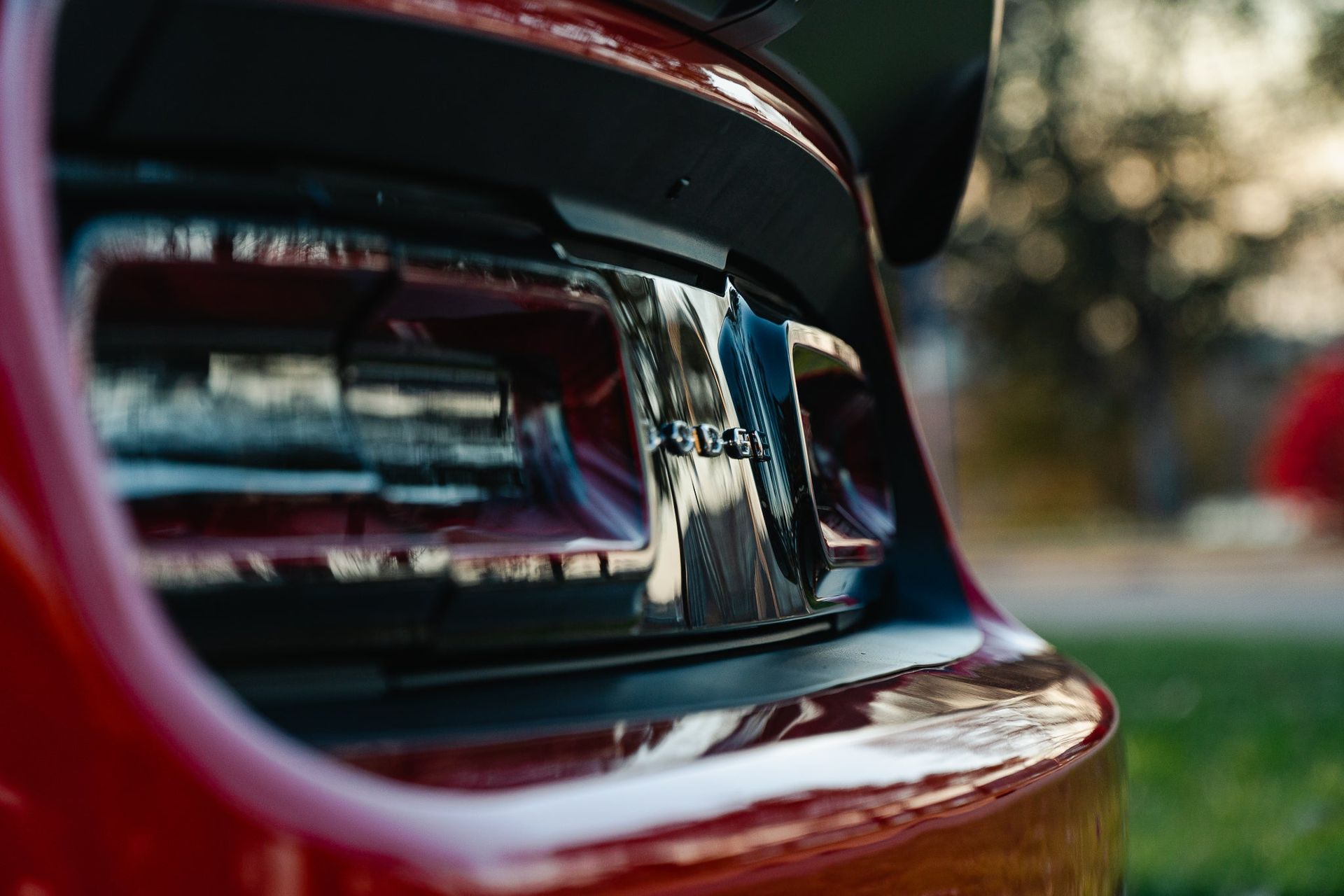 Close-up of a red car’s tail light with a blurred outdoor background