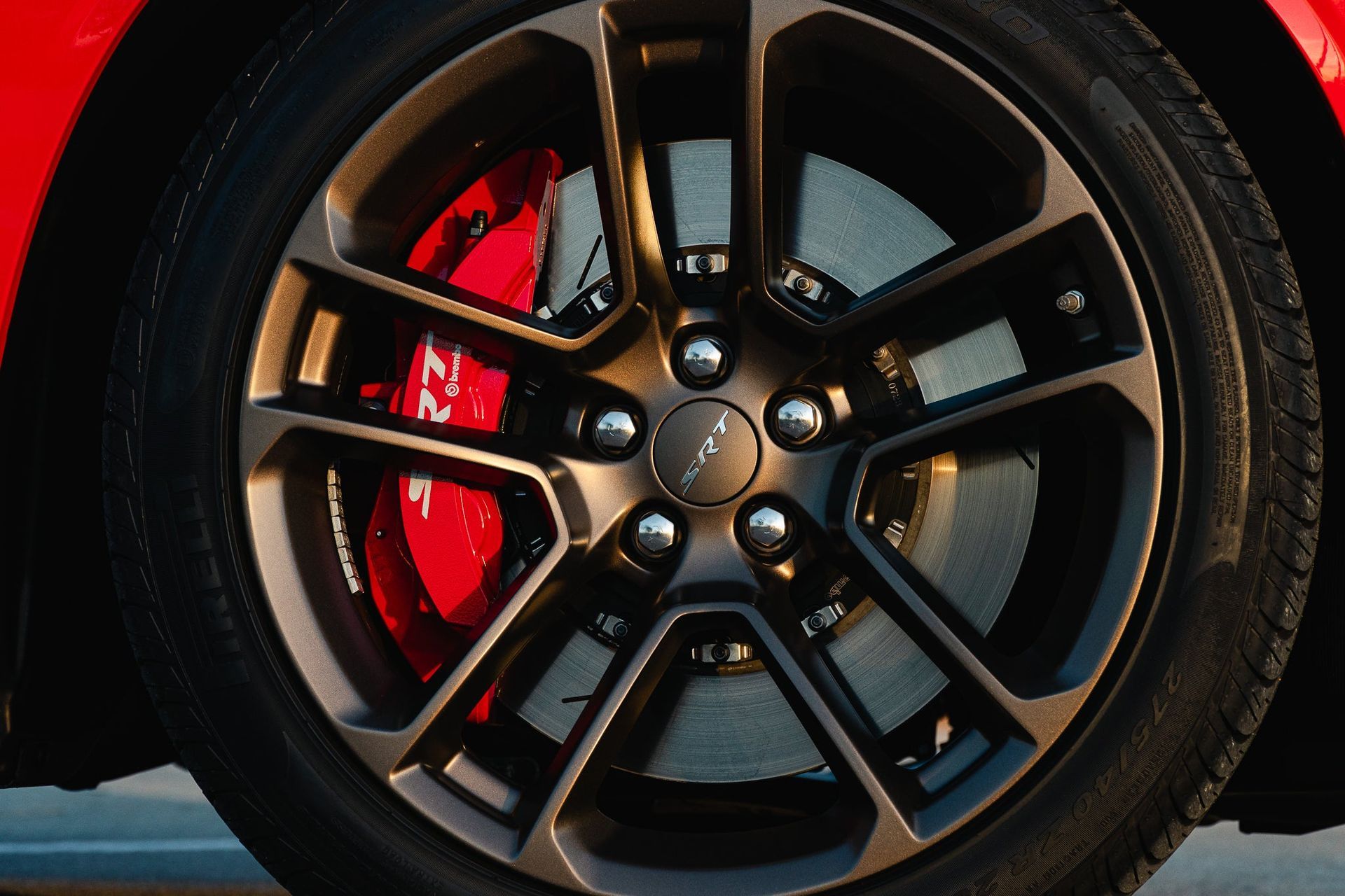 Close-up of a black car wheel with red brake caliper and dark alloy rim