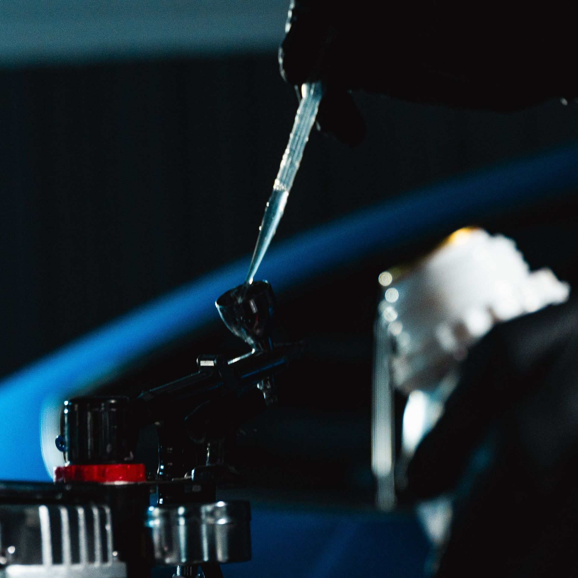 Close-up of a hand using a pipette to place a droplet on a lab device in dark lighting
