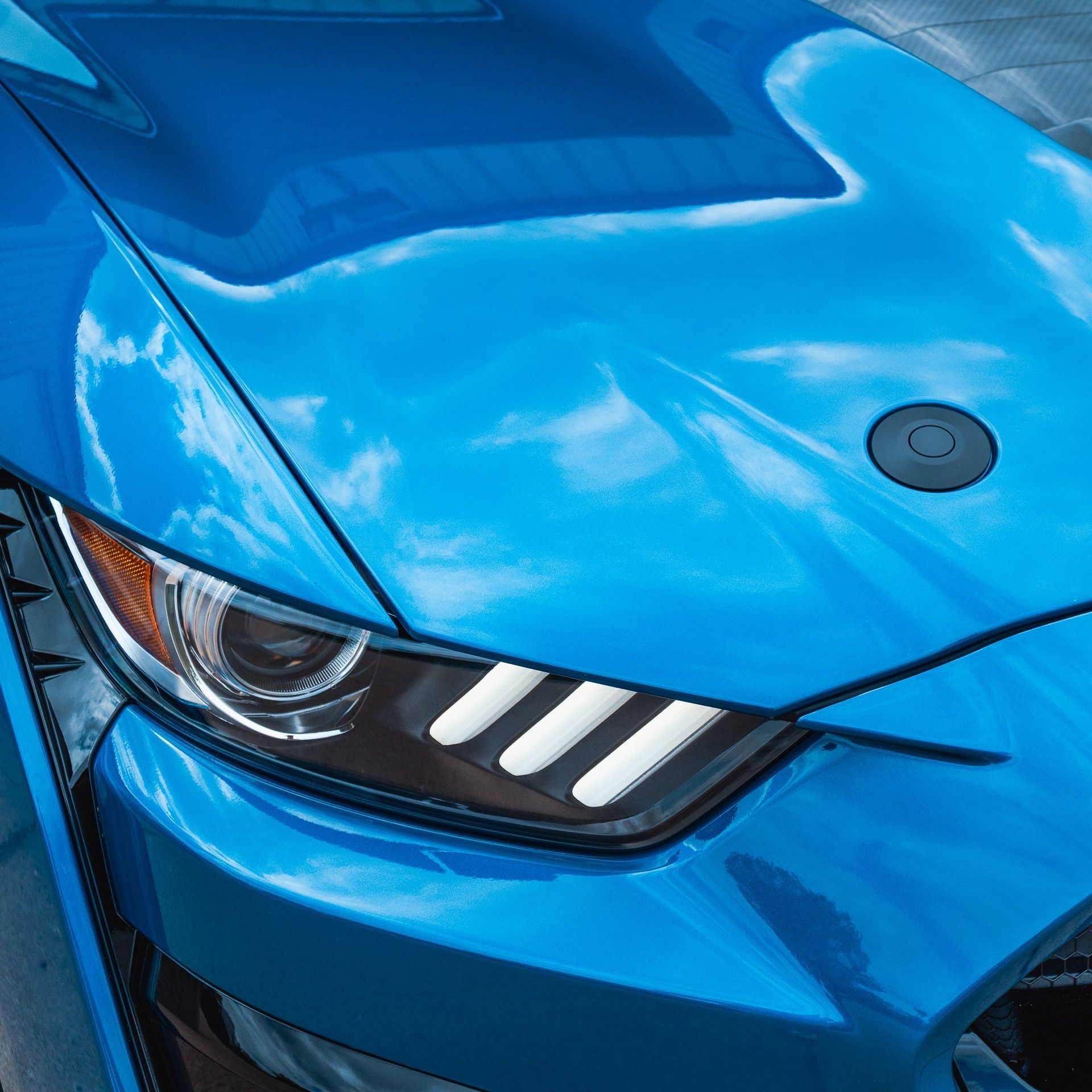 Close-up of a blue sports car front with sharp headlights and sleek hood details