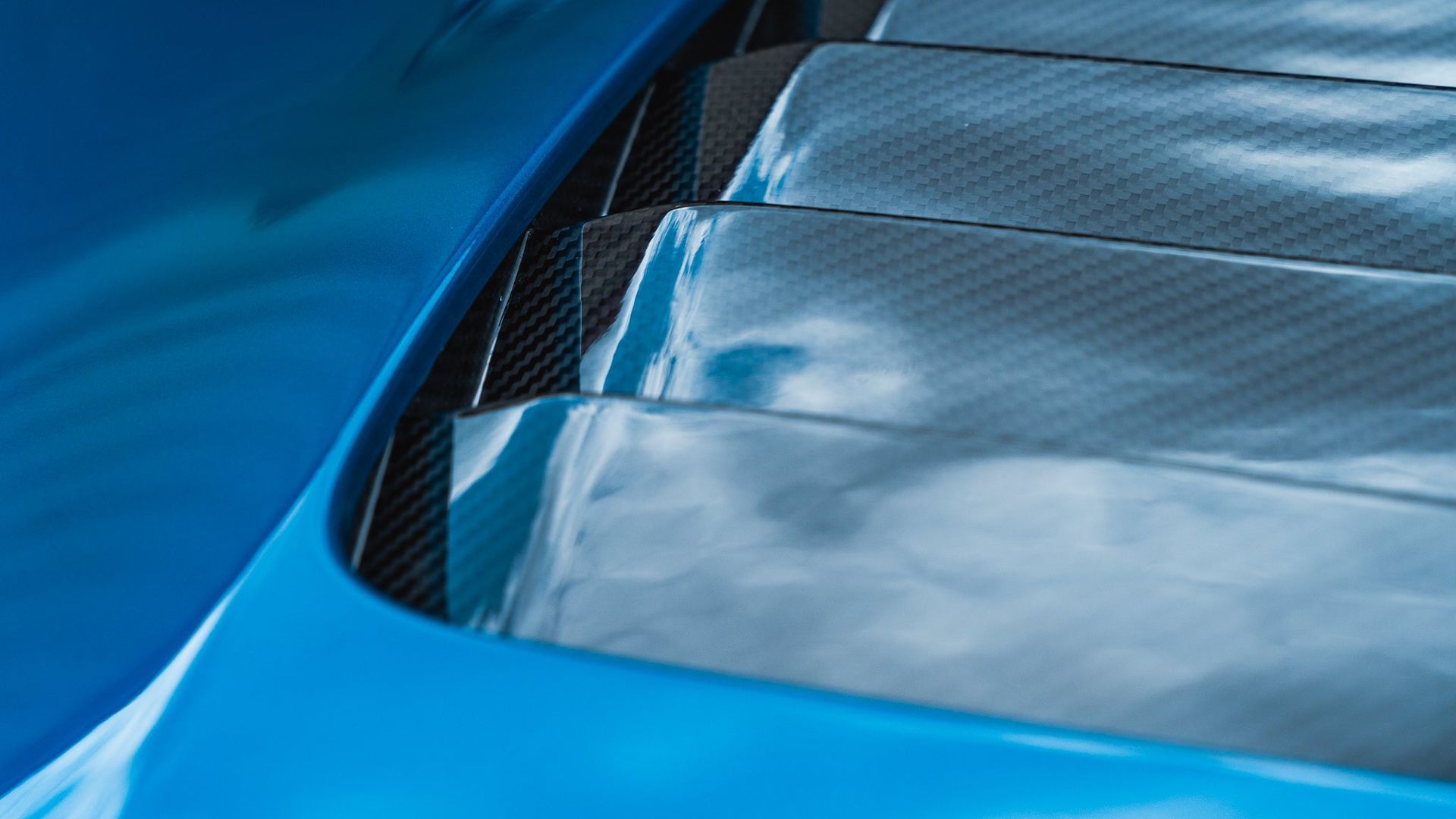 Close-up of a blue sports car rear vent and carbon fiber trim