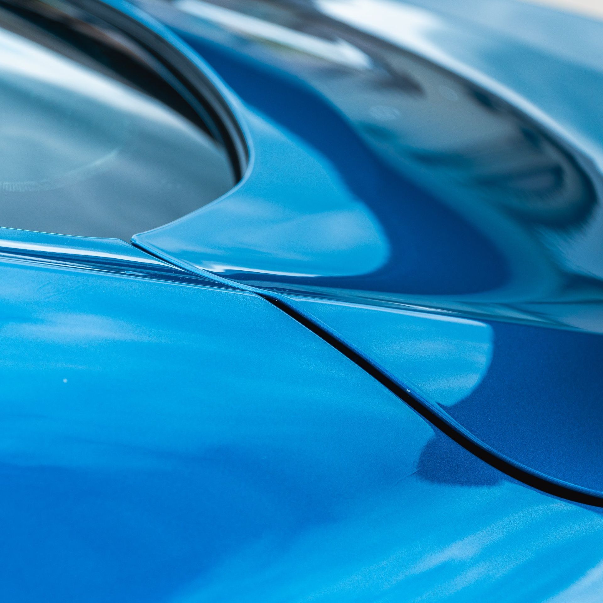 Close-up of a glossy blue car body and window seam.