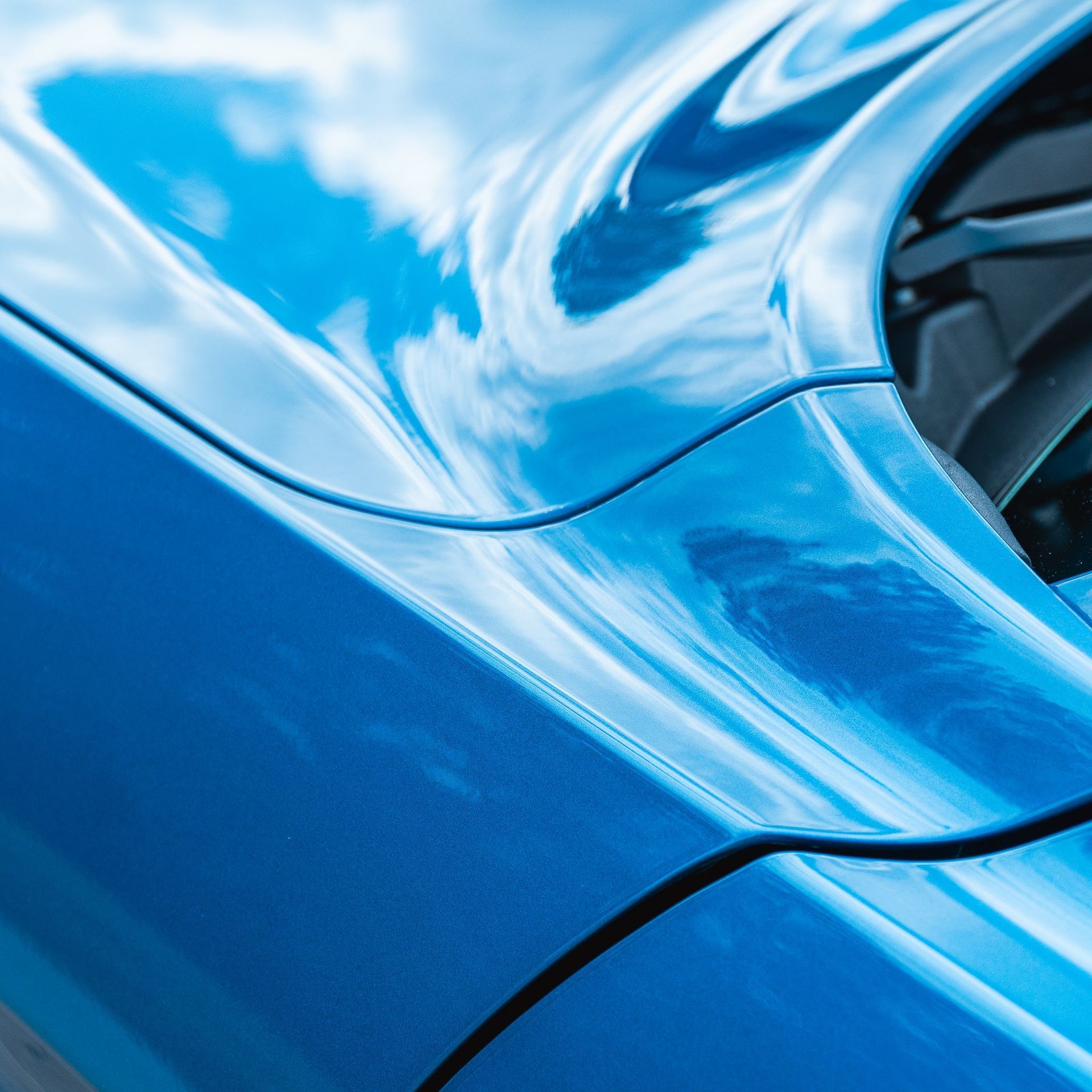Close-up of a glossy blue sports car body panel with a wheel arch