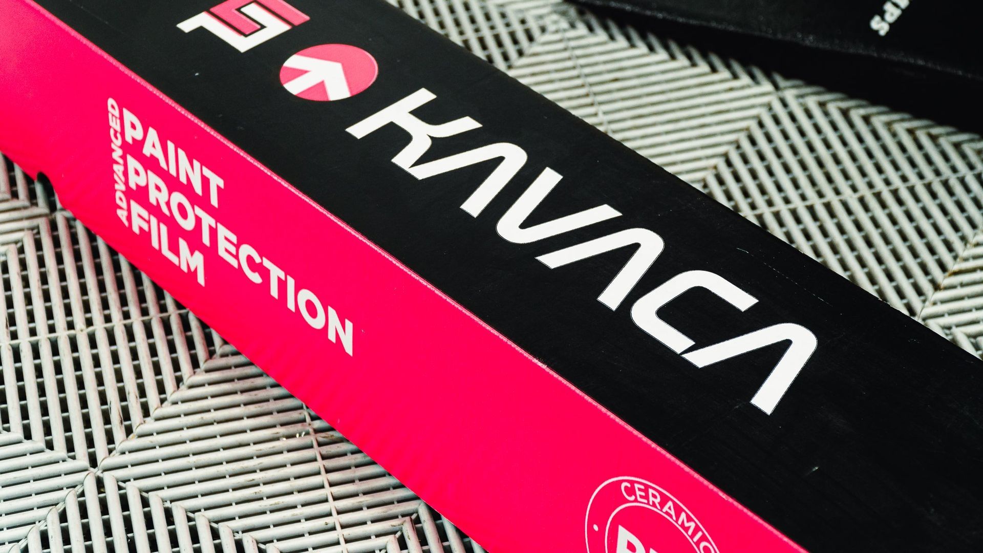Pink and black Kawasaki box labeled “Paint Protection,” resting on a striped surface.