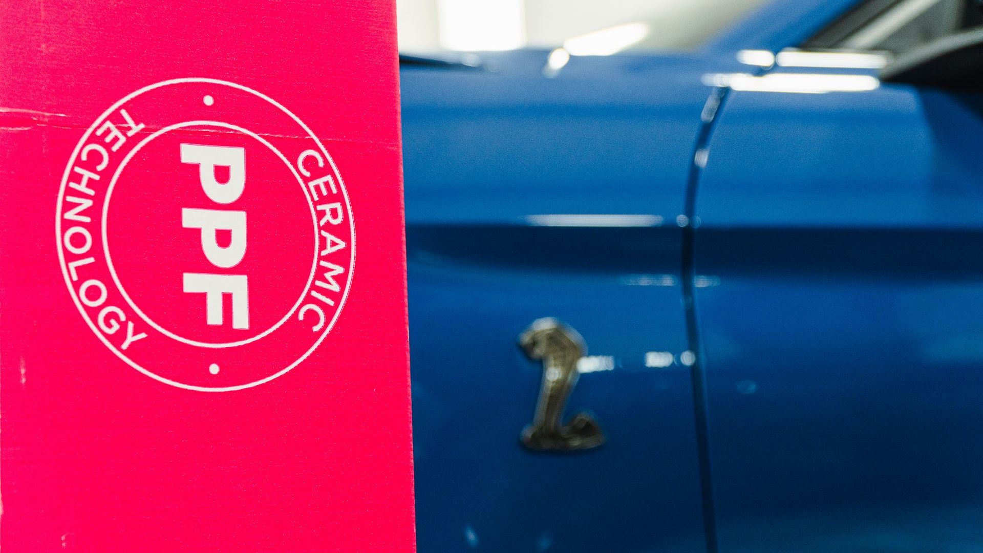 Red PPF Technology banner beside a blue car hood with a metallic hood ornament.