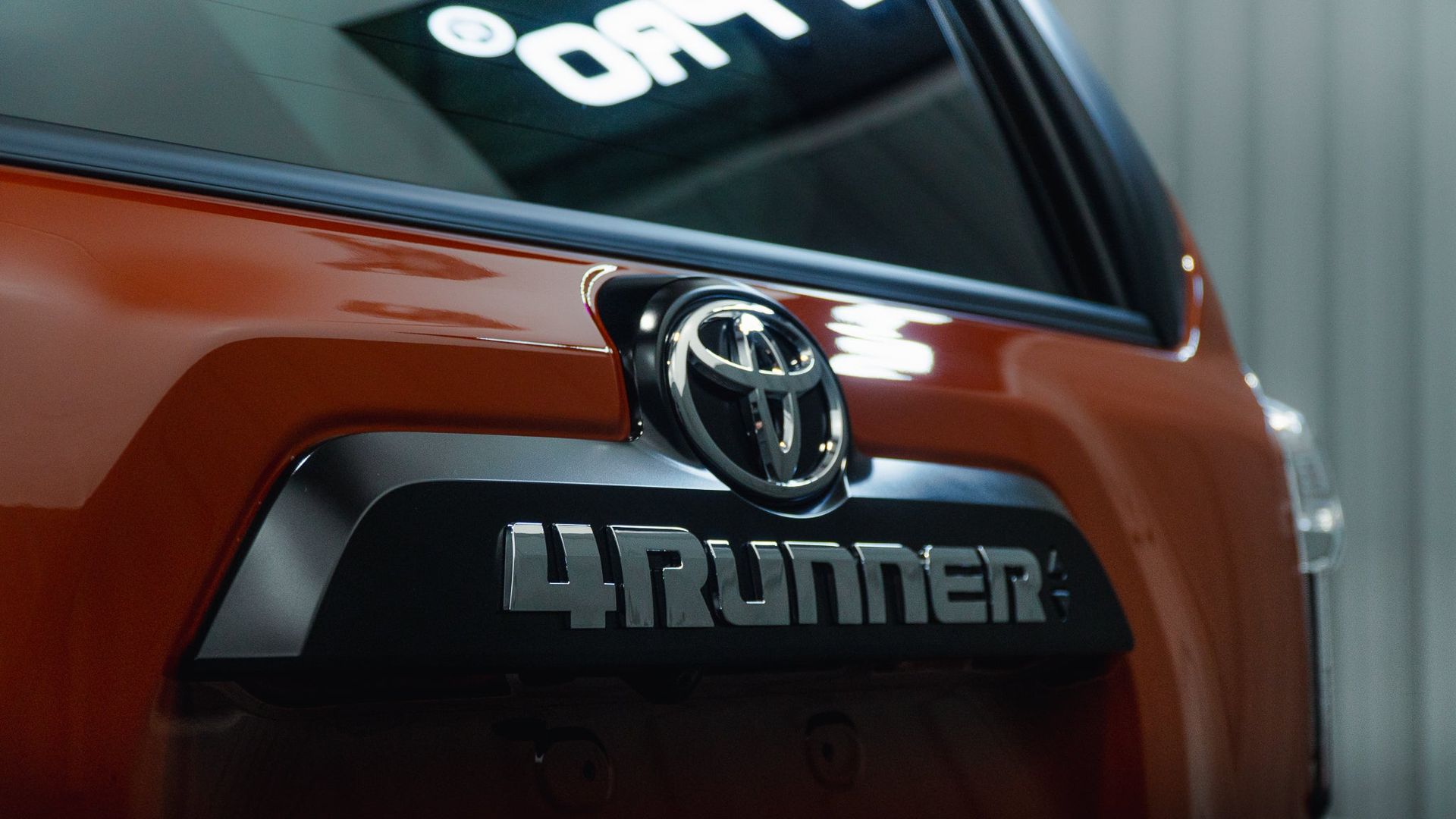 Rear view of a red Toyota 4Runner with chrome badge and emblem indoors