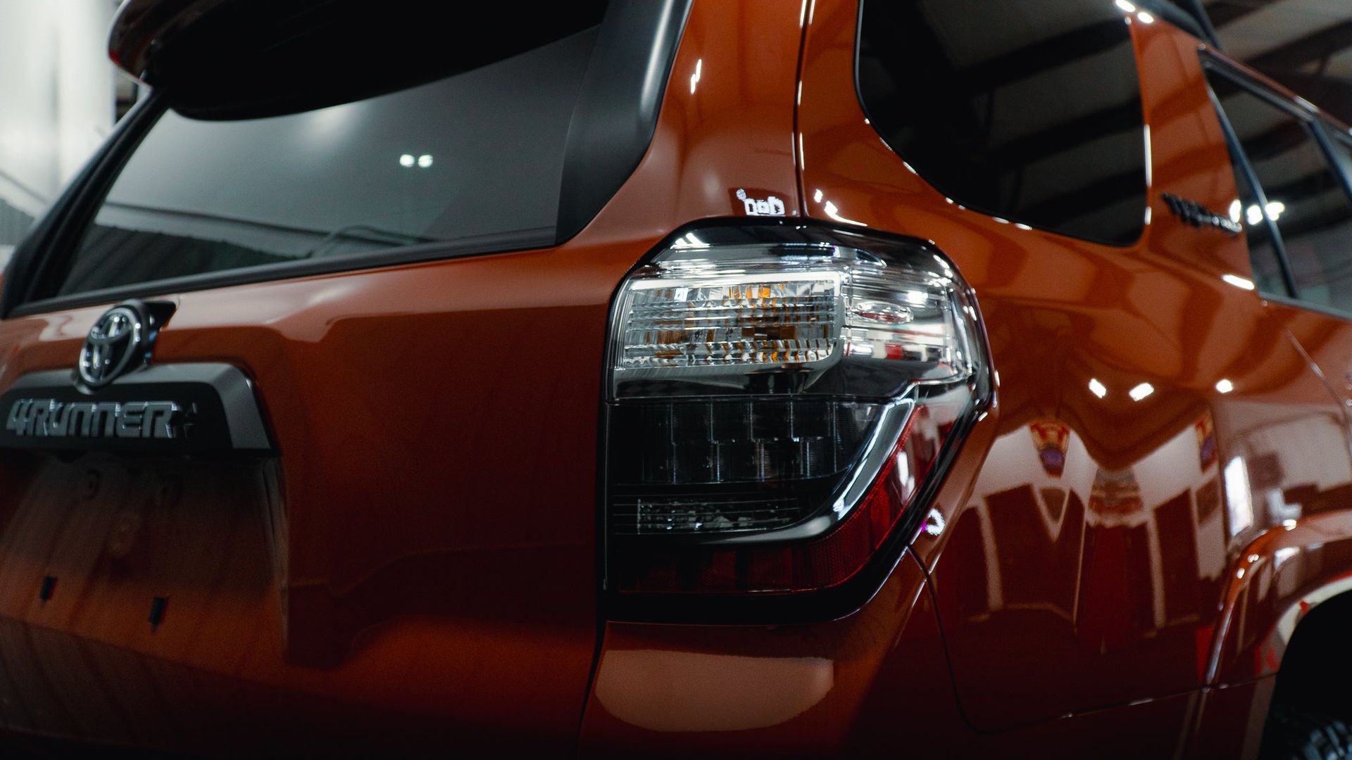 Close-up of a red SUV’s rear corner and taillight in a dim garage