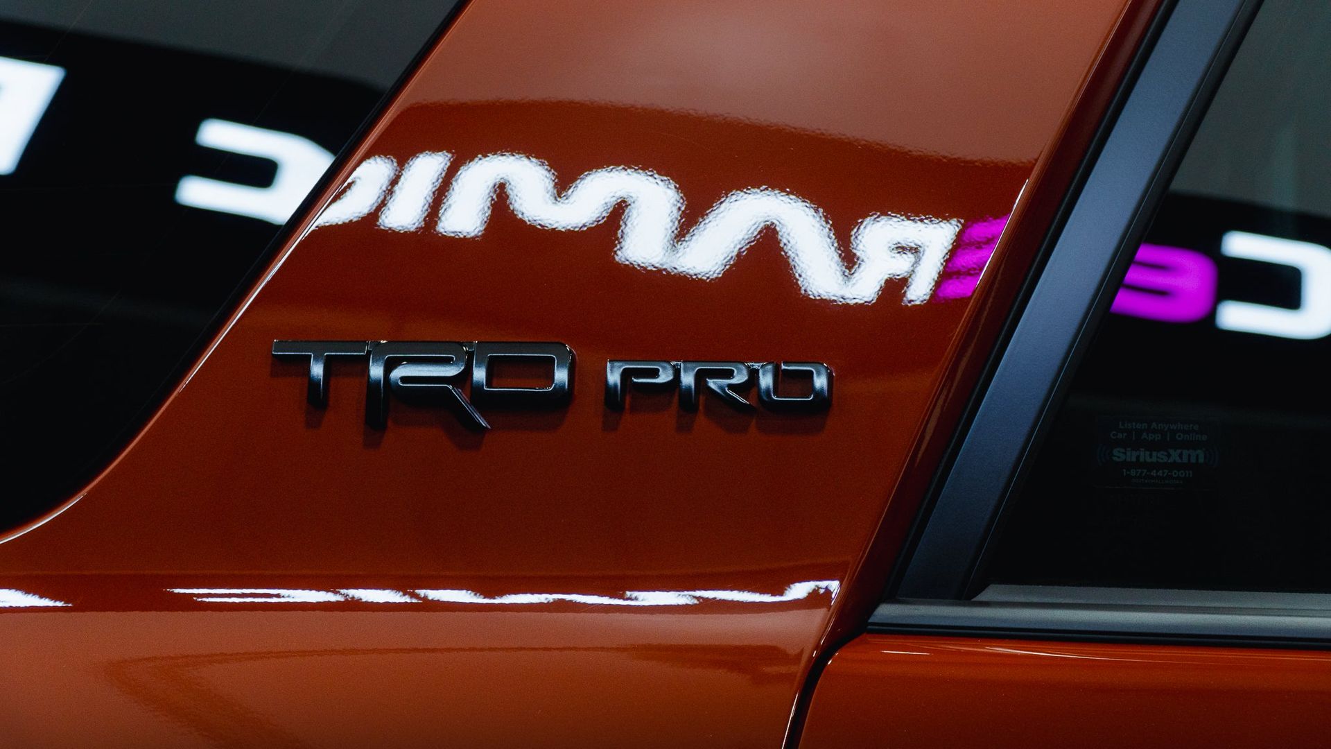 Close-up of a red car with black TRD PRO badging and mirrored lettering on the side window.