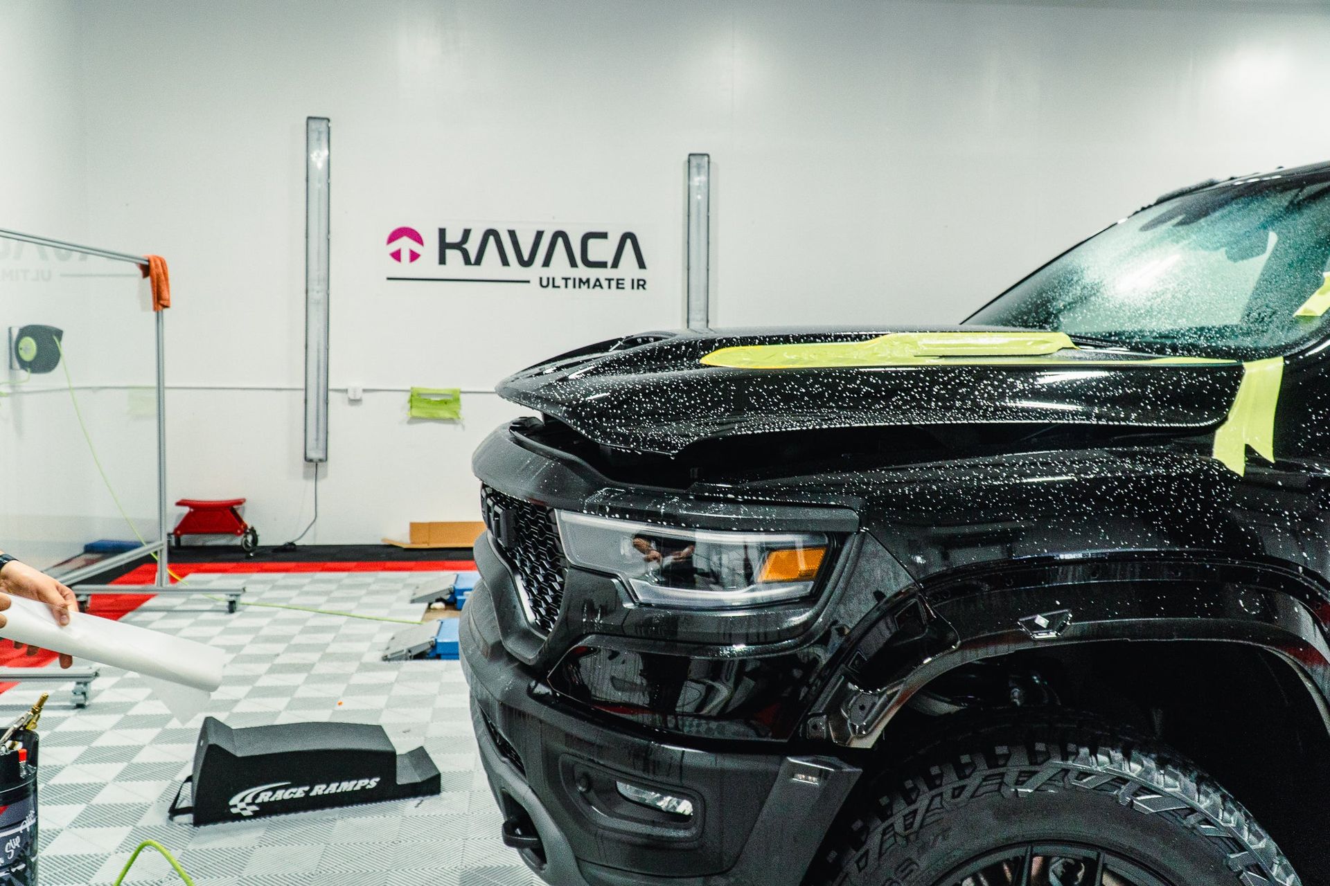 Black SUV being detailed in a bright auto shop, with water droplets and “Kavaca” signage in the background
