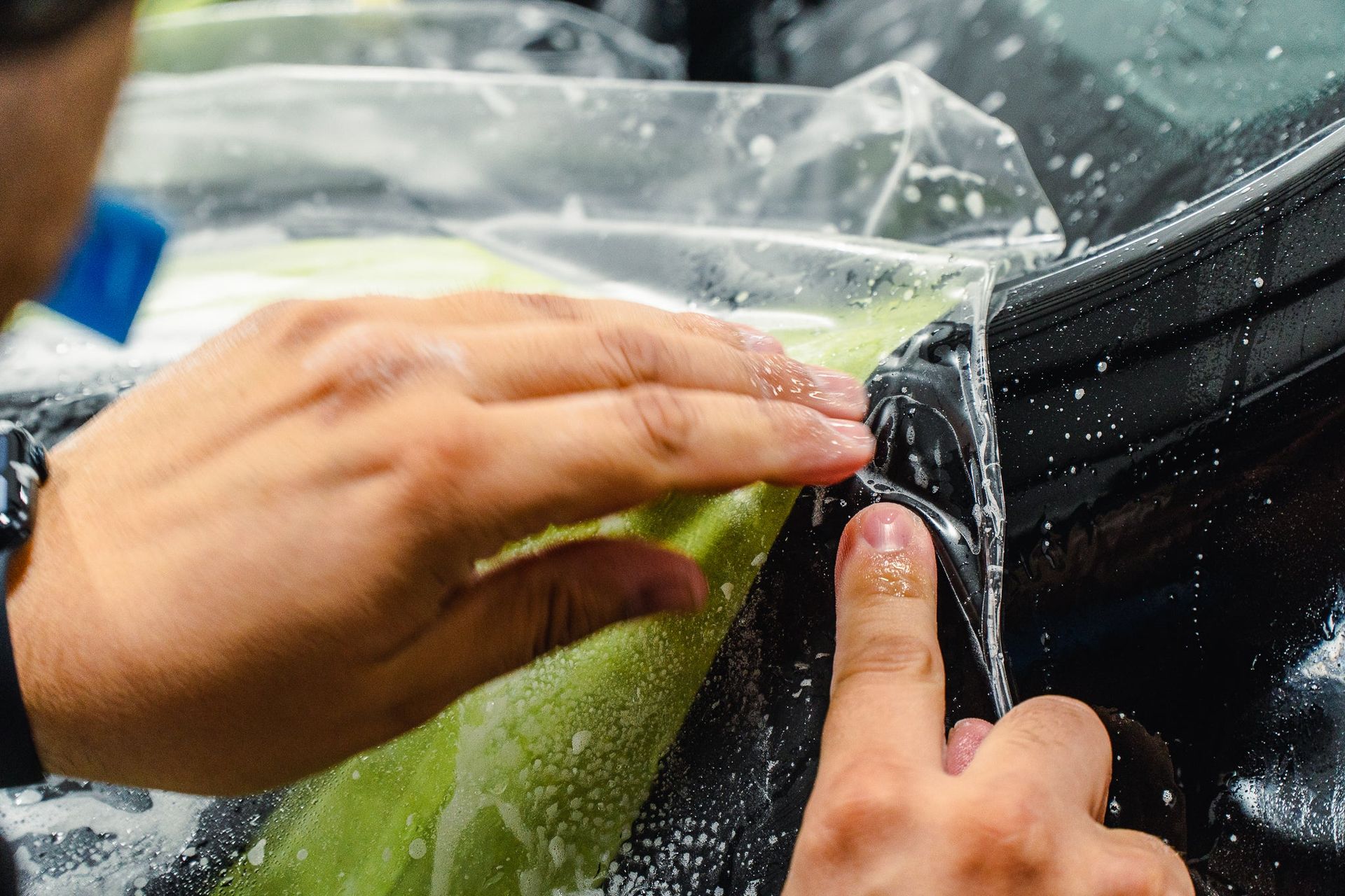 Hands sealing a clear plastic bag around green produce beside black fabric.