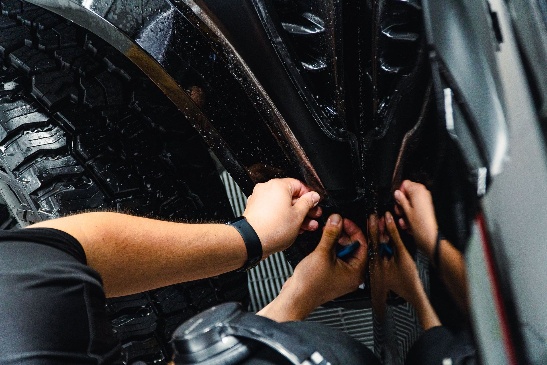 Hands working on a car tire and wheel assembly in a garage-like setting